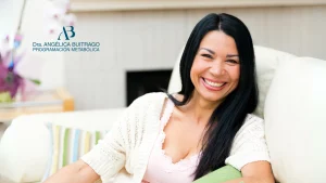 Mujer adulta sentada en un sofá claro, sonriendo con expresión cálida. En la parte izquierda de la imagen aparece el logo de la Doctora Metabolismo