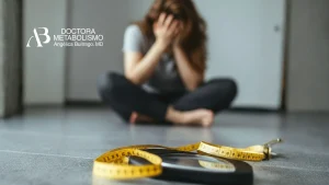Mujer sentada en el suelo con báscula y cinta métrica en primer plano, relacionada con sueroterapia metabolismo y control de peso en tratamiento médico especializado.