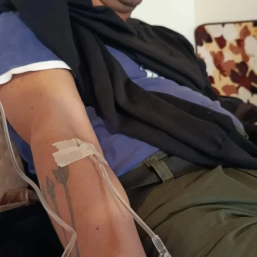Brazo de paciente juan carlos melo recibiendo sueroterapia con catéter intravenoso, sujeto con cinta médica y conectado a tubo de sueroterapia